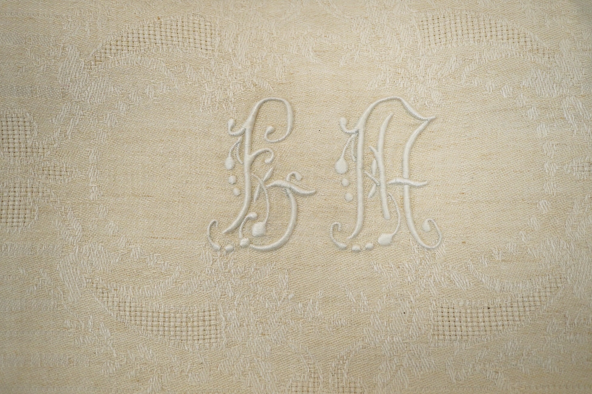 Twelve large damask dinner napkins, eleven smaller damask napkins, together with a cream monogrammed table cloth and twelve matching dinner napkins, cream monogrammed damask table cloth 230cm long x 152cm wide, matching